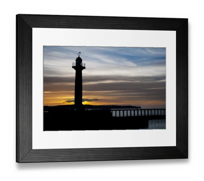 Framed Print : 19th century stone lighthouse on pier, silhouetted at sunset, West Pier, Whitby, North Yorkshire, England, April