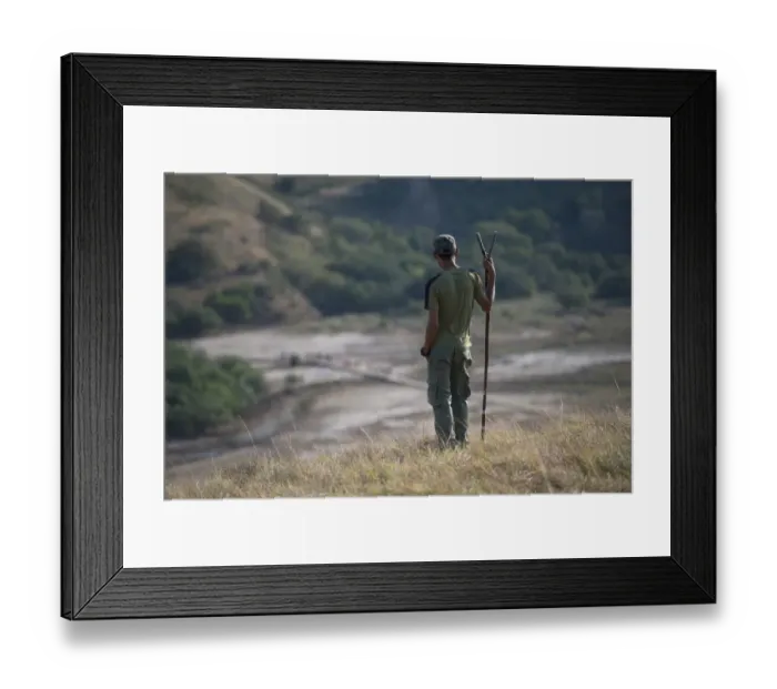 Framed Print : Park ranger with stick looking at tourists walking on path in background, Rinca Island, Komodo N. P Framed Print : Park ranger with stick looking at tourists walking on path in background, Rinca Island, Komodo N. P
