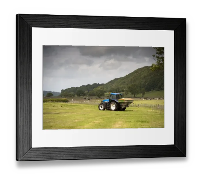 Framed Print : New Holland tractor with Amazone spreader, spreading fertiliser on meadow after taking crop of silage Framed Print : New Holland tractor with Amazone spreader, spreading fertiliser on meadow after taking crop of silage