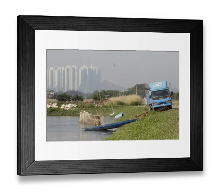 Framed Print : Commercial fishpond with sacks of fish food (bread crusts), boat, net and lorry, with skyscrapers in background