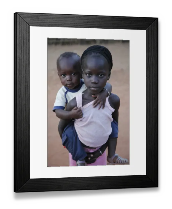 Framed Print : Young girl carrying younger brother on back, Gambia, january Framed Print : Young girl carrying younger brother on back, Gambia, january