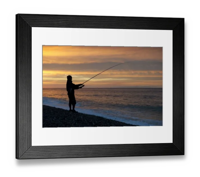 Framed Print : Sea angler fishing from shingle beach, silhouetted at sunset, Weybourne, Norfolk, England, august