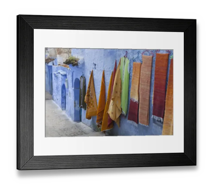 Framed Print : Blue houses and textiles for sale in alley of city, Chefchaouen, Morocco, april Framed Print : Blue houses and textiles for sale in alley of city, Chefchaouen, Morocco, april