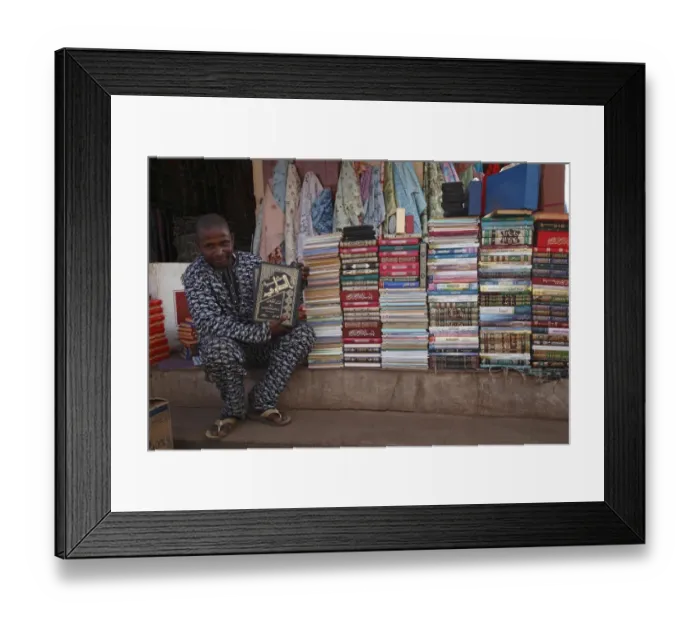 Framed Print : Salesman selling Koran books in market, Gambia, january Framed Print : Salesman selling Koran books in market, Gambia, january