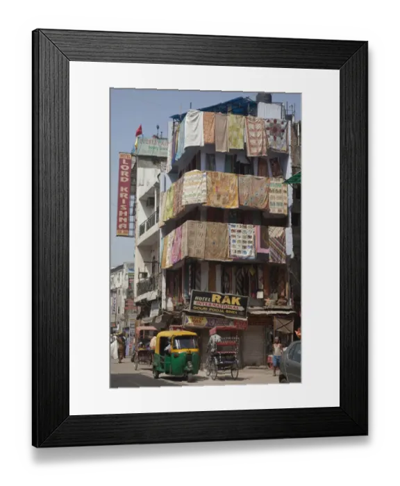 Framed Print : View of city street with rickshaws, hotels and shop selling rugs, Delhi, India Framed Print : View of city street with rickshaws, hotels and shop selling rugs, Delhi, India