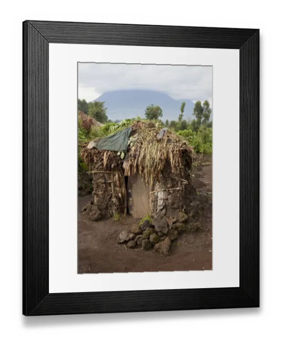 Framed Print : Mud hut in Pygmy village, with volcano in background, Virunga Mountains, Uganda