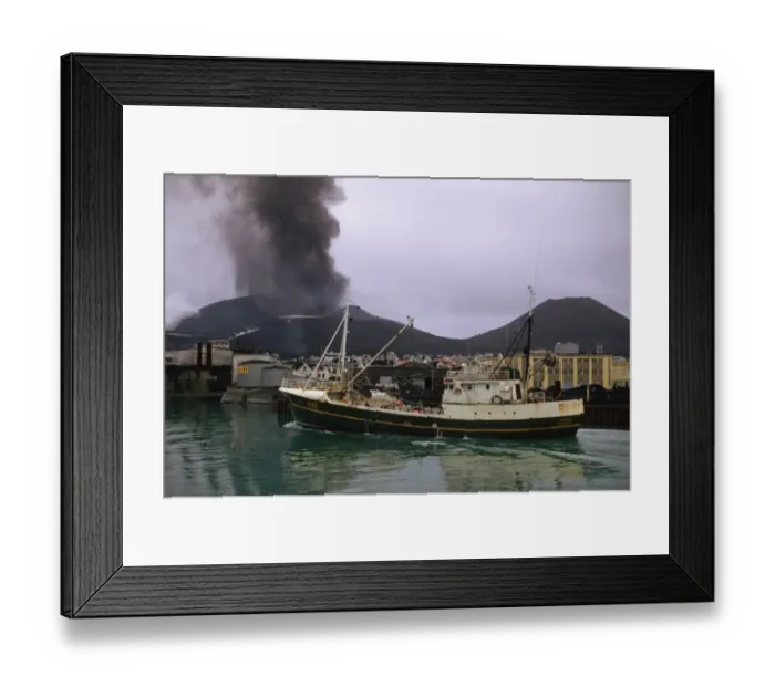 Framed Print : Fishing boat leaving harbour, with ash raising from erupting volcano in background, Eldfell Volcano, Heimaey Framed Print : Fishing boat leaving harbour, with ash raising from erupting volcano in background, Eldfell Volcano, Heimaey