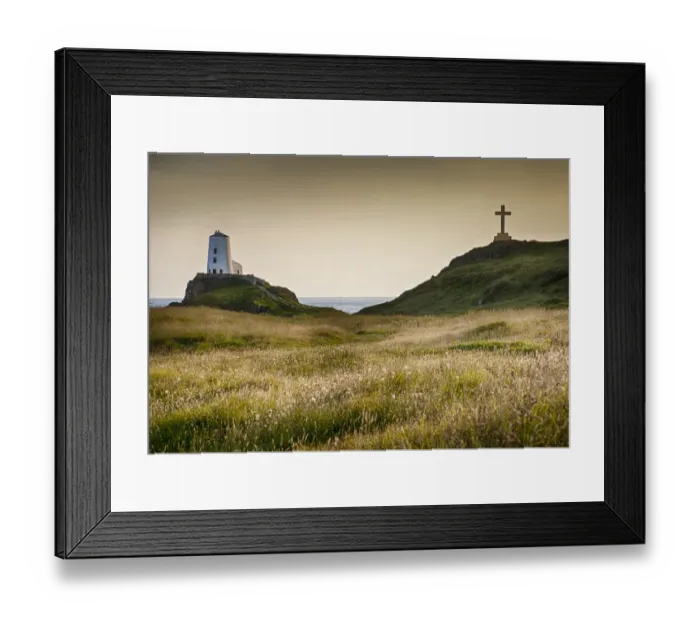 Framed Print : View of lighthouse, cross and coastline on tidal island, Llanddwyn Island, Newborough Warren National Nature Reserve