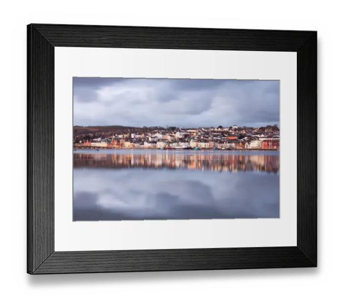 Framed Print : View across estuary at high tide towards town with glow from lights, with rainclouds gathering overhead at dawn