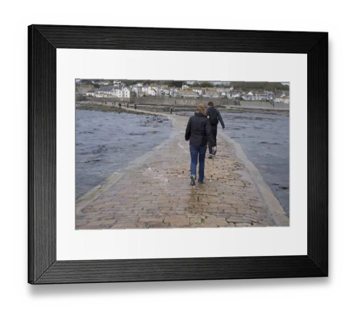 Framed Print : Tourists walking in seawater covering manmade causeway from tidal island, St