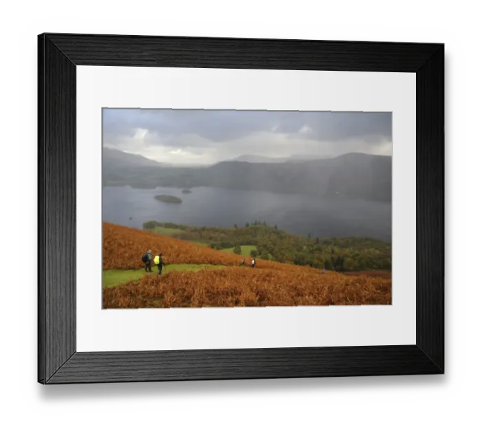 Framed Print : View of walkers descending through bracken covered fellside towards lake with rain squall overhead Framed Print : View of walkers descending through bracken covered fellside towards lake with rain squall overhead