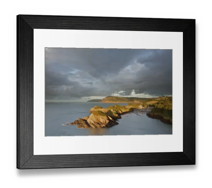 Framed Print : Rainclouds gathering over rocky coastal peninsula and bay in evening, with Great Hangmans and Combemartin in distance Framed Print : Rainclouds gathering over rocky coastal peninsula and bay in evening, with Great Hangmans and Combemartin in distance