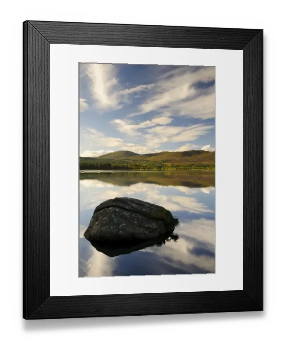 Framed Print : View of blue sky, clouds and rock reflected in still water of freshwater loch, Loch Garten, Abernethy Forest