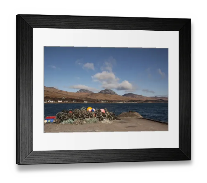 Framed Print : Lobster pots on Jura Pier with the village of Craighouse and the Paps of Jura Framed Print : Lobster pots on Jura Pier with the village of Craighouse and the Paps of Jura
