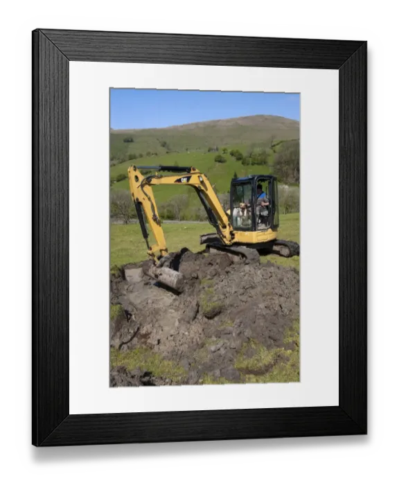Framed Print : Farmer repairing old blocked drain in upland meadow using mini digger, Cumbria, England, May