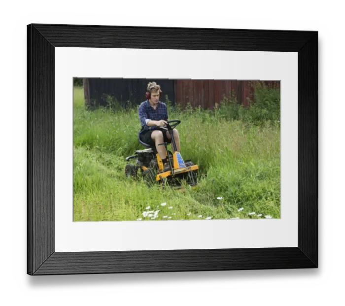 Framed Print : Man using ride-on mower on farm, cutting long grass around sheds, Sweden Framed Print : Man using ride-on mower on farm, cutting long grass around sheds, Sweden