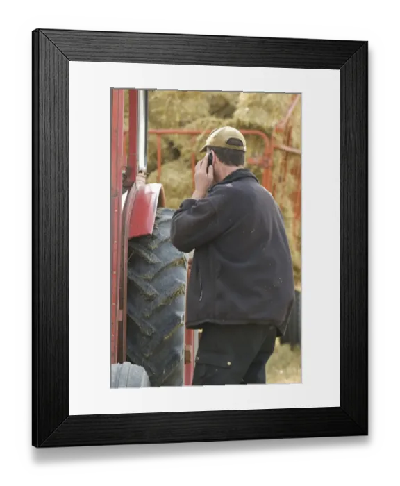 Framed Print : Farmer talking on mobile phone, standing beside tractor and trailer with straw bales, Sweden Framed Print : Farmer talking on mobile phone, standing beside tractor and trailer with straw bales, Sweden