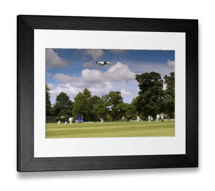 Framed Print : Cricket match being played on village pitch, on summer afternoon, underneath flight path to Manchester International Framed Print : Cricket match being played on village pitch, on summer afternoon, underneath flight path to Manchester International