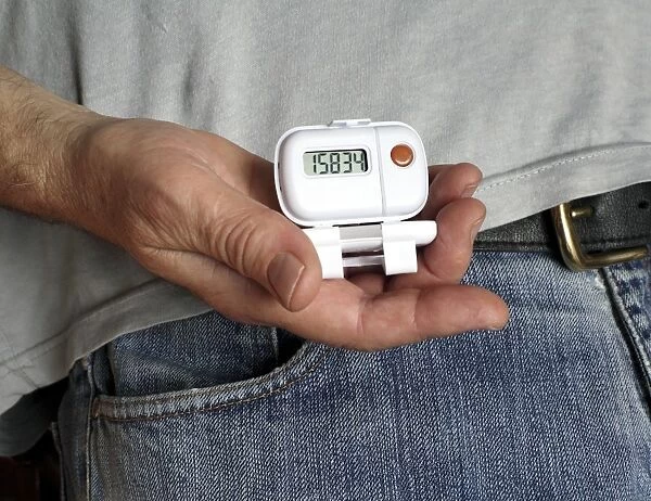 Pedometer. MODEL RELEASED. Man holding a pedometer