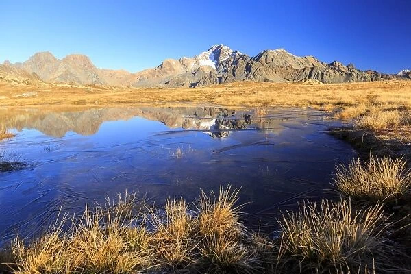 Blue lake frames the peaks of Mount Disgrazia and Cornibruciati, Val Torreggio, Malenco Valley