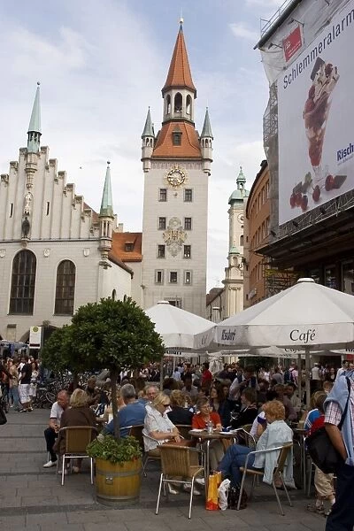 People sitting at an outdoors cafe in front of the old city hall
