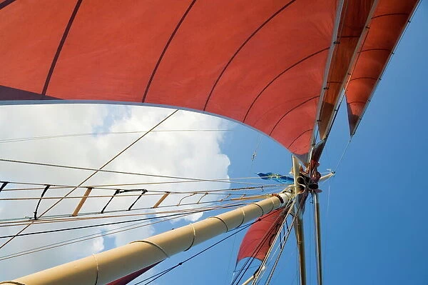 Red sails on sailboat that takes tourists out for sunset cruise