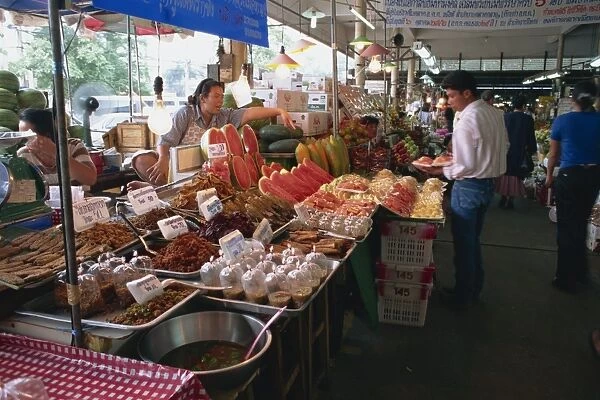A shopkeeper pointing at fruit on one of the food stalls