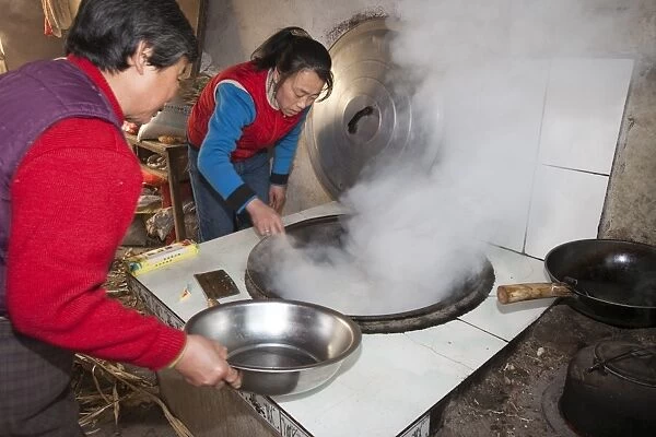 A Chinese family cooks on a stove fuelled by dried corn stalks and husks which not only cooks the food and heats the water but also heats the house. People living such a lifestyle have a very small carbon footprint, though an increasingly aspirant