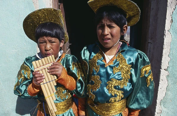 10087466. BOLIVIA Potosi Two boys in costume blowing pipe