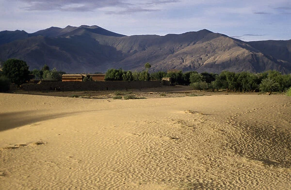 10089405. CHINA Tibet Samye Wind rippled encroaching sand with mountain backdrop