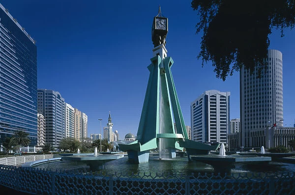 20013683. UAE Abu Dhabi City centre clock tower with fountain underneath modern structure