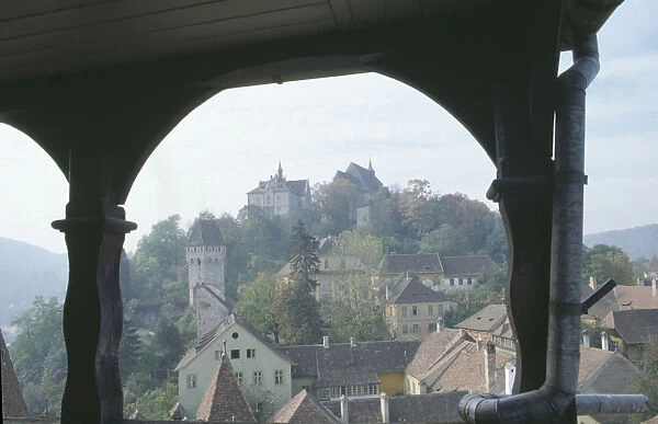20055846. ROMANIA Mures Sighisoara. View of town rooftops framed by archway