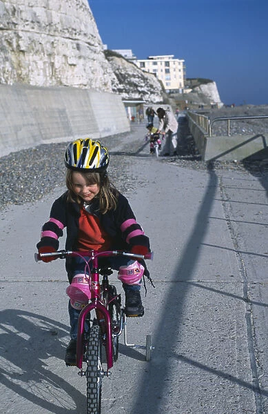 20059883. CHILDREN Playing Young girl on a bicycle dressed in protective cycling helmet
