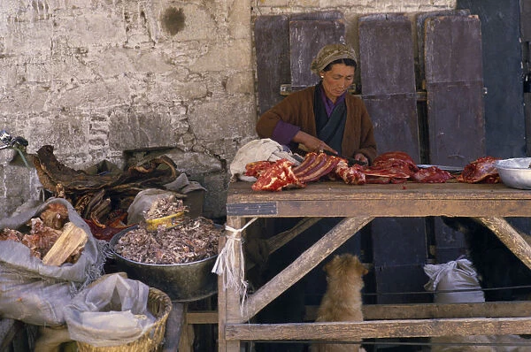 20076364. TIBET Lhasa Female vendor with yak meat for sale in Jokhang market