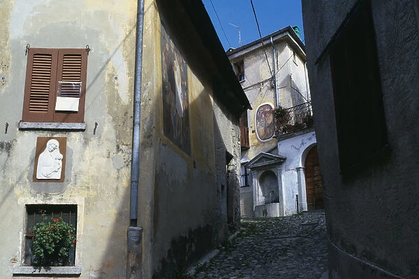 20088260. ITALY Lombardy Arcumeggia Narrow cobbled street with fresco decoration