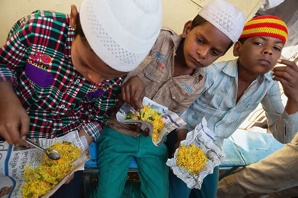 India, Maharashtra, Dhule, Muslim boys eating chana choor served from a street stall