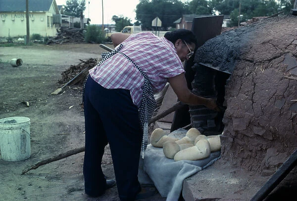 USA, New Mexico, Zuni Zuni Pueblo Native American Indian woman making bread in a Horno