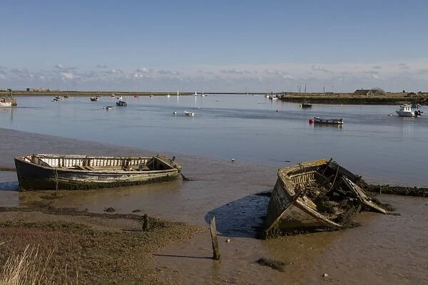 Abandoned boats on the mud flats of the River Ore near Orford, Suffolk. Orford ness on the right