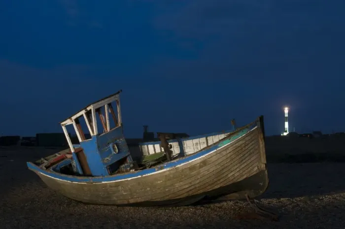Framed Print : Abandoned fishing boat on shingle beach with distant lighthouse at night, Dungeness, Kent, England, April Framed Print : Abandoned fishing boat on shingle beach with distant lighthouse at night, Dungeness, Kent, England, April