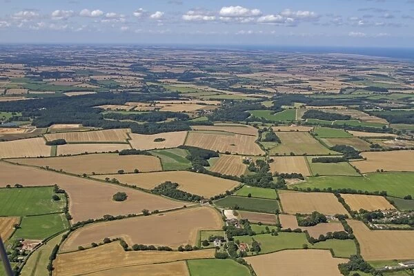 Aerial view of farmland with arable fields, hedgerows and woodland, North Norfolk, England, August