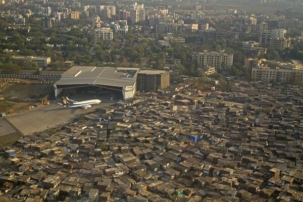 Aerial view of slum areas surrounded by luxury apartments, offices and airport, India, February