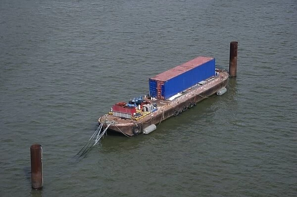 Barge with container moored on river in city, River Thames, London, England, april
