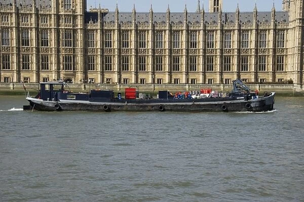 Barge on river beside Palace of Westminster (Houses of Parliament), River Thames, Westminster, London, England, april