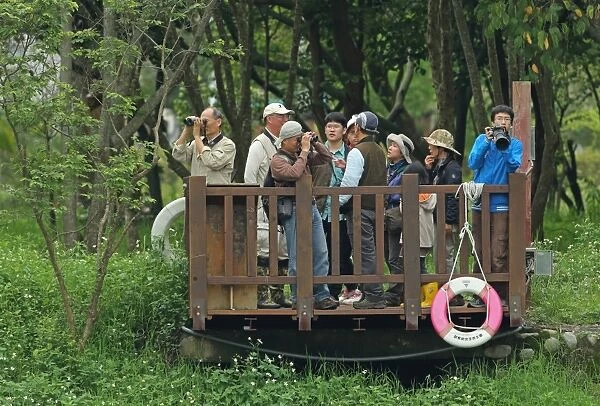Birdwatchers with binoculars and camera on platform, contestants in bird race