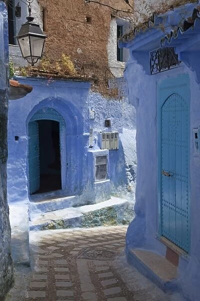 Blue door and buildings in alley of city, Chefchaouen, Morocco, april