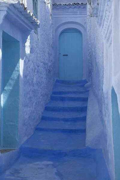 Blue door, buildings and stairway in alley of city, Chefchaouen, Morocco, april