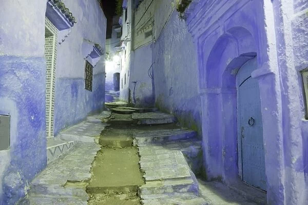 Blue door and houses in alley of city at night, Chefchaouen, Morocco, april
