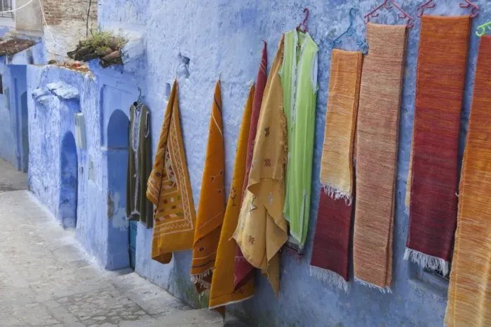 Framed Print : Blue houses and textiles for sale in alley of city, Chefchaouen, Morocco, april Framed Print : Blue houses and textiles for sale in alley of city, Chefchaouen, Morocco, april