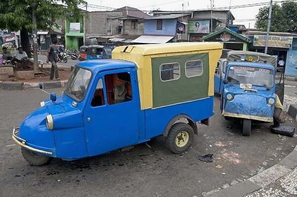 Blue tuk tuk three-wheeler vans on road in city, Manggarai District, Jakarta, Java, Indonesia, December