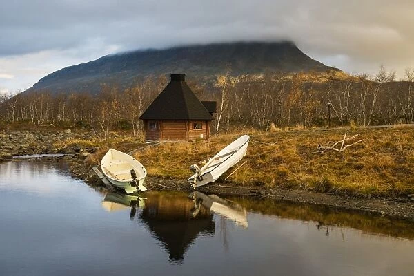 Boats moored on lake shore with Kota (hut), with summit of Saana Fell in background, Lake Kilpis, Kilpisjarvi